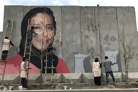 Artists paint a mural of Hamida Barmaki, who, along with her husband and children, was killed in a 2011 suicide attack, on a blast wall near the home of warlord Gulbuddin Hekmatyar, whose followers carried out the attack. (Photo| AFP)
