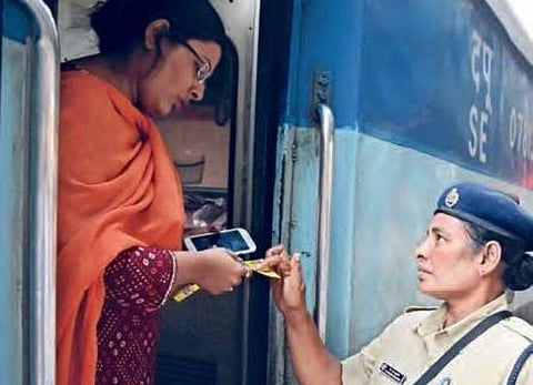 An RPF cop distributing a pamphlet on women safety to a passenger in Vijayawada railway station on Wednesday | Express