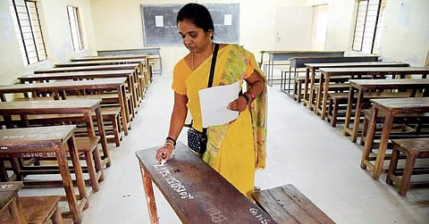 A staff writes register number ahead of SSLC examinations at a government school near Malleswaram in Bengaluru on Thursday | nagaraja gadekal