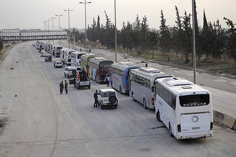 Syrian government forces oversee the evacuation by buses of rebel fighters and their families, at a checkpoint in eastern Ghouta, Syria. (AP)