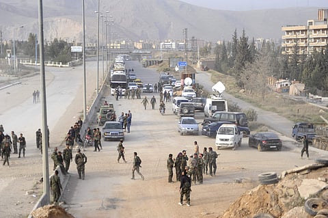 Syrian government forces oversee the evacuation by buses of rebel fighters and their families, at a checkpoint in eastern Ghouta | AP