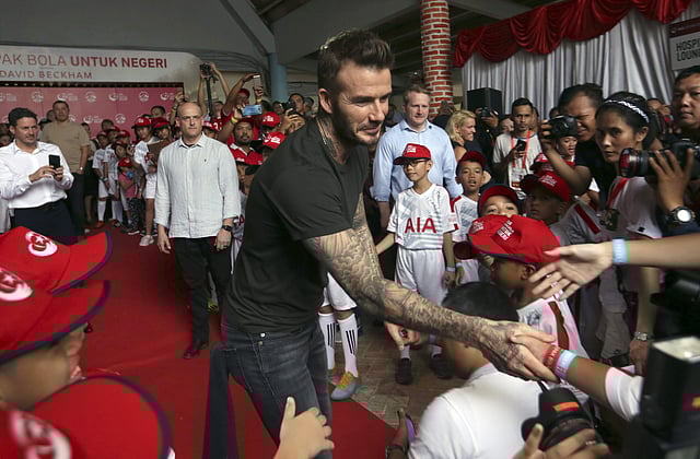 Former British soccer star David Beckham, center, is greeted by Indonesian children during a promotional event in Jakarta. | AP