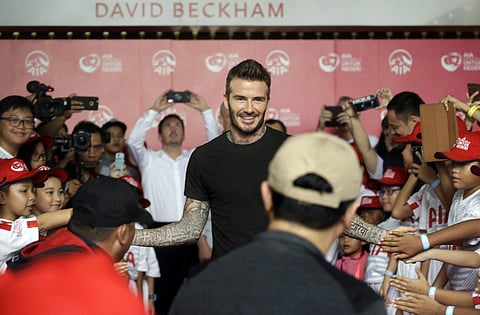 Former British soccer star David Beckham, center, is greeted by Indonesian children during a promotional event in Jakarta. | AP