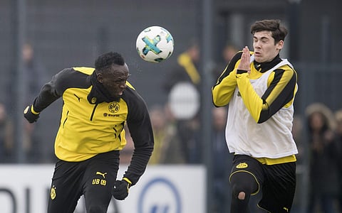 Jamaica's former sprinter Usain Bolt, left, heads the ball towards Dortmund's Tim Sechelmann, U19 team, during a practice session of the Borussia Dortmund soccer squad. | AP