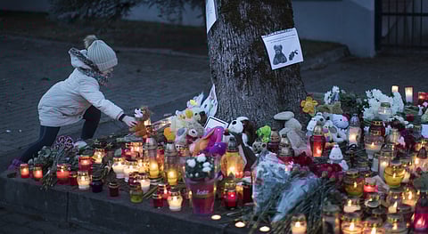A girl lays a toy to commemorate the victims of Sunday's fire in a shopping mall in the Siberian city of Kemerovo, in front of the Russia's Embassy in Vilnius, Lithuania. | AP