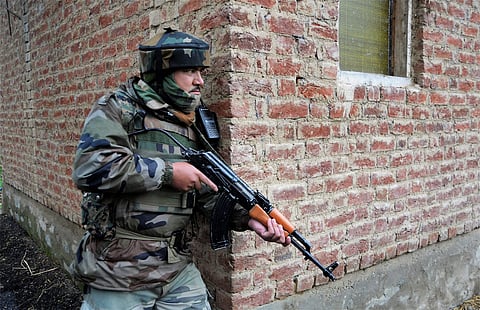 An army personnel takes his position near a house during a gunfight between militants and the security forces. 