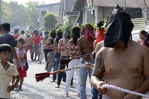 Residents watch as Filipino hooded penitents flagellate during Good Friday rituals in San Fernando, Pampanga province, northern Philippines. | AP
