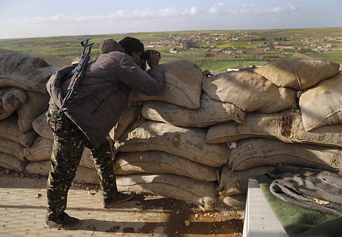 A fighter from the U.S-backed Syrian Manbij Military Council looks through his binoculars to Turkish-backed fighters' positions, at the front line of Halawanji village, north of Manbij town, Syria. 