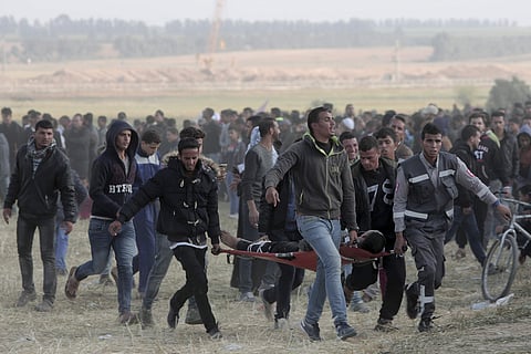 Palestinian protesters evacuate a wounded youth during clashes with Israeli troops along the Gaza Strip border with Israel, east of Khan Younis, Gaza Strip. | AP
