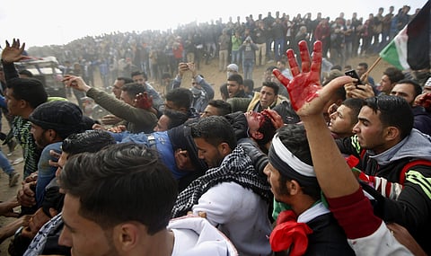 Palestinian protesters evacuate a wounded youth during clashes with Israeli troops along the Gaza Strip border with Israel, east of Khan Younis, Gaza Strip. | AP