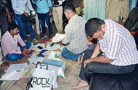 ACB sleuths examine the documents seized during a raid on the house of a tainted official in Vizag on Saturday | Express
