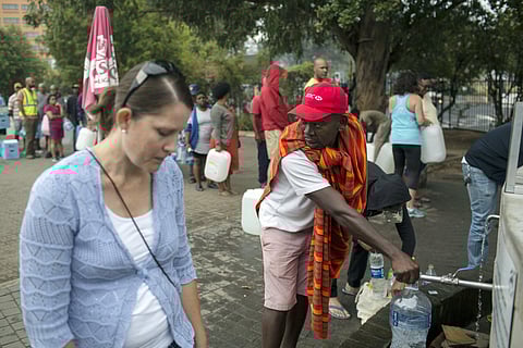 Residents fill containers with water at a source for natural spring water in Cape Town, South Africa (AP)