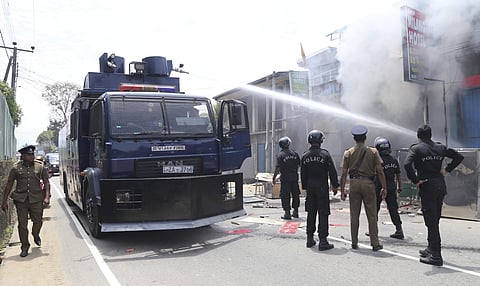 Sri Lankan police officers attempt to douse burning shops in Ambatenna, in central Sri Lanka. | AP
