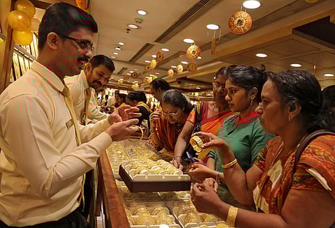 A salesman shows gold bangles to customer inside a jewellery showroom on the occasion of Akshaya Tritiya, a major gold buying festival, in Kochi. (Photo | Reuters)