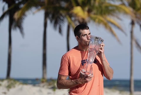 John Isner poses with his trophy on Crandon Park Beach, after defeating Alexander Zverev in the men's final at the Miami Open. | AP