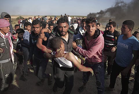 Palestinian protesters carry a wounded man who was shot by Israeli troops during a protest near the Gaza Strip | AP