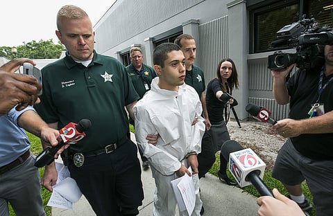 Marion County Sheriff's Detectives John Lightle, left, and Dan Pinder, right, escort a handcuffed and shackled Sky Bouche, 19, center, to a waiting patrol car. (AP)