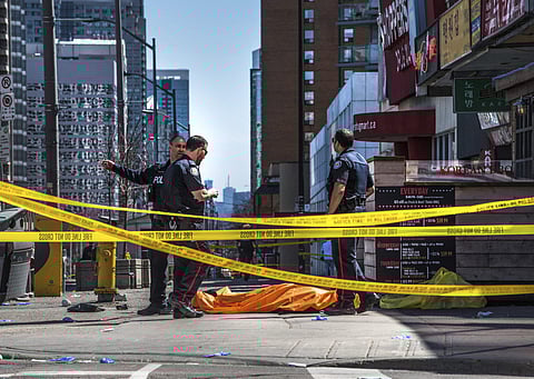 A rented van ploughed down a crowded Toronto sidewalk on Monday, killing 10 people and injuring 15. IN PIC: Police secure an area around a covered body. (Photo: AP)
