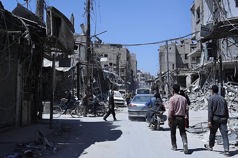 People walk among damaged buildings in Syria (File Photo | AP)
