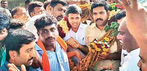 BJP workers garland B Y Vijayendra and party candidate Preetham Nagappa  in Hanur on Saturday