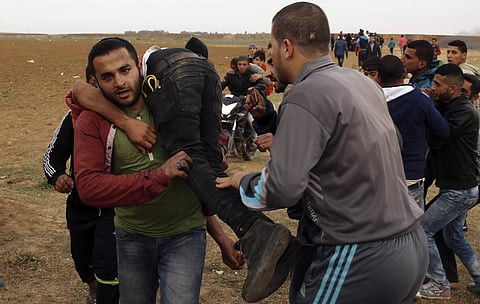 Palestinian protesters evacuate a wounded youth during clashes with Israeli troops along Gaza's border with Israel, east of Beit Lahiya, Gaza Strip, Tuesday, April 3, 2018. | Associated Press