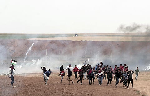Palestinian protesters run to take cover from teargas during clashes with Israeli troops along the Gaza's border with Israel | AP