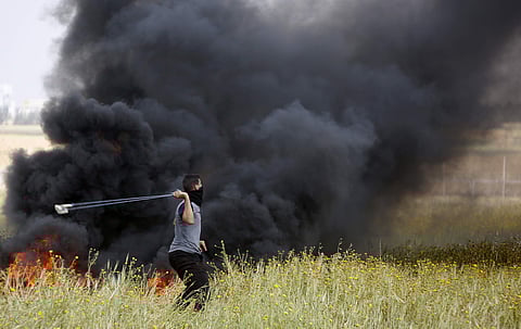 A Palestinian protester slings stones towards Israeli soldiers during clashes with Israeli troops along the Gaza Strip border with Israel, east of Khan Younis, Gaza Strip. | File AP