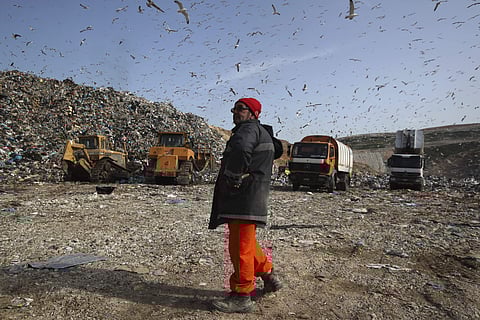 In this Wednesday, Feb. 2, 2018 photo a worker gives directions to the truck drivers at the country's largest landfill at Fyli on the outskirts of Athens. Greece has the European Union’s longest coastline, poor waste management and an addiction to single-use plastic that littering the country’s seabed. To fight the problems, volunteer divers are working as underwater garbage collectors to clear debris - mostly plastic - that is littering the sea floor. | AP