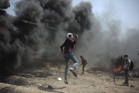 A Palestinian protester hurls stones at Israeli troops during a protest at the Gaza Strip's border with Israel, Friday, April 6, 2018. | AP