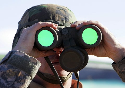 A New York National Guard keeps an eye on a group of suspected illegal immigrants near the Arizona-Mexico border (AP File Photo)