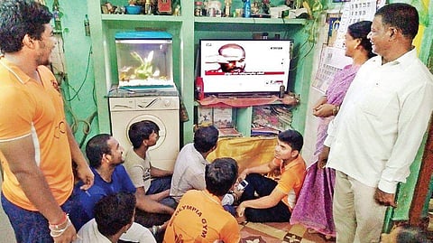Sathish’s family (mother and father to the right and brother to the left) and youth from the locality watching the live telecast of the event, in Vellore on Saturday | Express