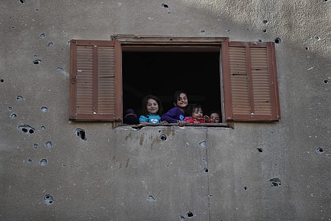 In this Thursday, April 5, 2018 photo, children look from the window of their house that was damaged last summer during fighting between U.S.-backed Syrian Democratic Forces fighters and Islamic State militants, in Raqqa, Syria. | AP