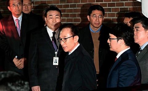 Former South Korean President Lee Myung-bak, center, gets into a car as he is transferred to a detention center, at his residence in Seoul, South Korea. | AP