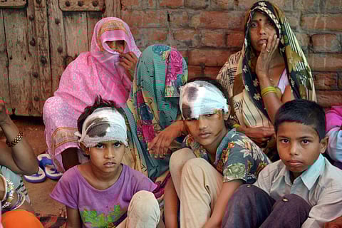 Children who were injured after their house collapsed in the recent storm sit with their family members at Arjuna village in Khandauli Agra on Thursday. | PTI
