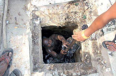 A GHMC contract worker cleans a manhole near NTR Gardens on Necklace Road, in Hyderabad on Friday| sathya keerthi