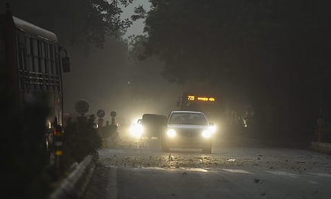 Vehicles ply at a road with headlights on as visibility hets poor due to a storm and rains in New Delhi on Sunday. | PTI