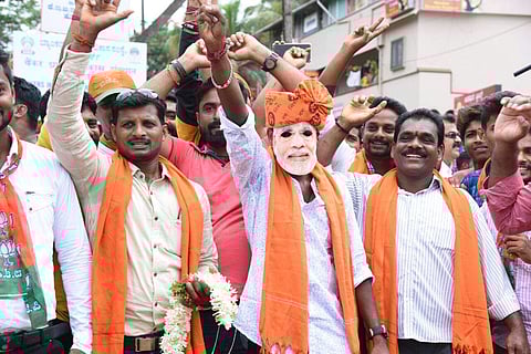 A man wears a Modi mask and celebrates BJP win in Mangaluru. (EPS| Rajesh)