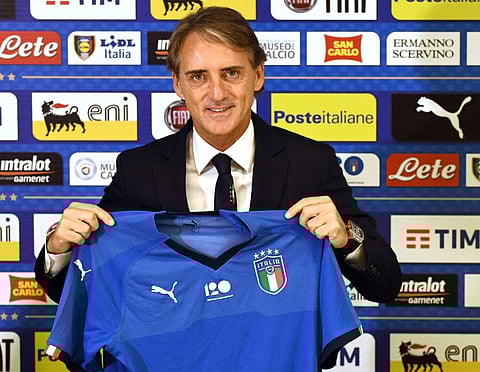 Italy's soccer national team new coach Roberto Mancini shows a jersey of the Italian team during his first press conference at Coverciano Sporting Center, in Florence. | AP