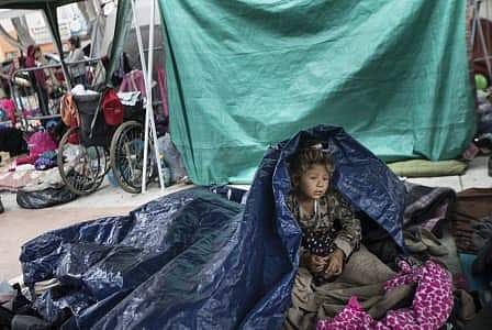 A girl who traveled with the annual caravan of Central American migrants awakens where the group set up camp to wait for access to request asylum in the U.S. (Photo | AP)