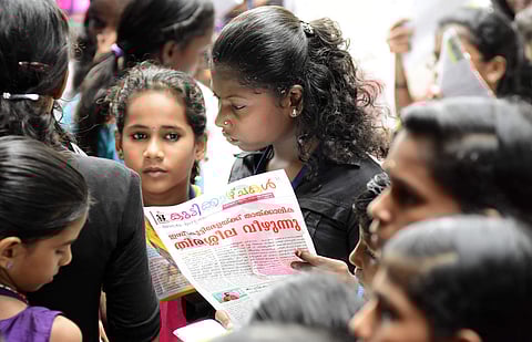 Delegates going through the festival bulletin in the final day of the International Children's Film Festival of Kerala at Kairali theater in Thiruvananthapuram on Sunday. Express Photo | BP Deepu