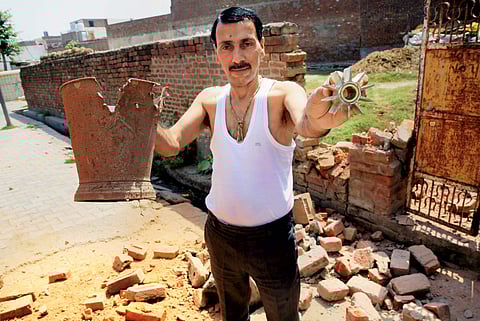 A villager shows parts of mortar shell allegedly fired from the Pakistani side along the international border at Arnia sector in Jammu on Tuesday. | PTI