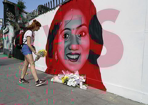 A woman places flowers by a mural showing Savita Halappanavar, a 31-year-old Indian dentist who had sought and been denied an abortion before she died after a miscarriage, with the word YES over it, in Ireland, on the day of a referendum on the 8th amendm