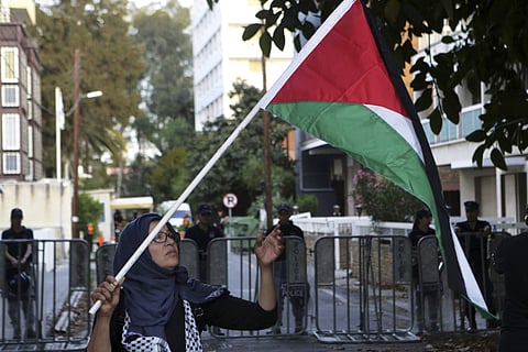 A Palestinian woman who lives in Cyprus, holds up the Palestine flag in front of the riot police behind the barricades during a protest outside from the Israeli embassy in Nicosia, Cyprus, Wednesday, May 16 , 2018. | AP