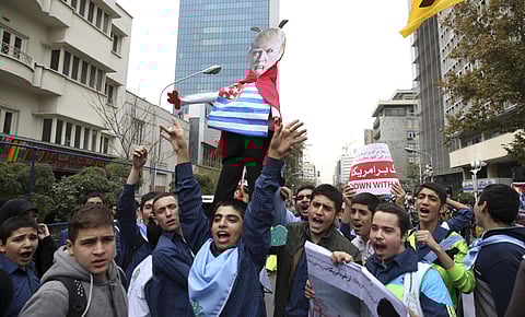 FILE- In this Nov. 4, 2017 file photo, Iranian schoolboys chant slogan while holding an effigy of U.S. President Donald Trump in an annual gathering in front of the former U.S. Embassy marking the anniversary of its 1979 takeover in Tehran, Iran. (Photo| 