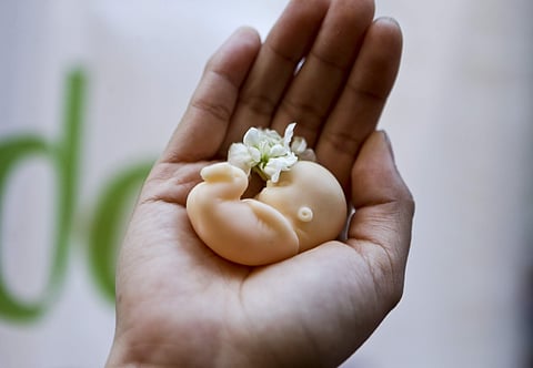 A woman holds a fetus doll in the palm of her hand (Photo | AP)