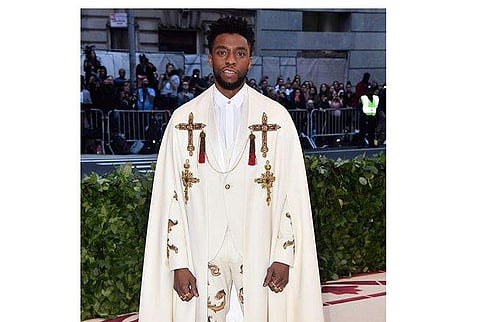 Chadwick Boseman in a a white, custom-made, Atelier Versace tuxedo with gold beading with and matching bejeweled cross cape at the 2018 Met Gala. (Instagram/Versace)
