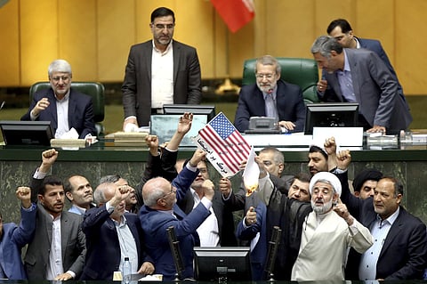 Iranian lawmakers burn two pieces of papers representing the U.S. flag and the nuclear deal as they chant slogans against the U.S. at the parliament in Tehran. (Photo | AP)