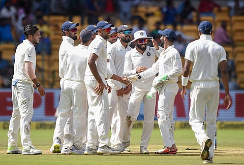 Indian cricketer Umesh Yadav with teammates celebrate the wicket of Afghanistan batsman Mohammad Nabi during the second day of a one-off test match at M Chinnaswamy Stadium in Bengaluru. | PTI