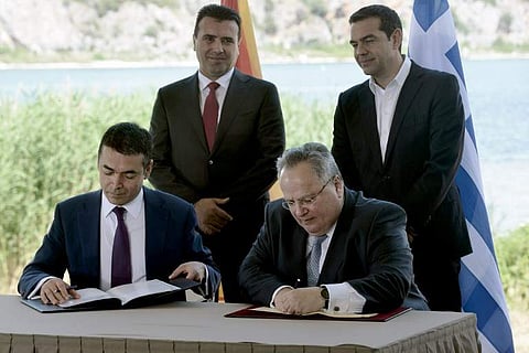 Greek Foreign Minister Nikos Kotzias (down, R) and his Macedonian counterpart Nikola Dimitrov (down, L) sign a preliminary accord as Greek Prime Minister Alexis Tsipras (R) and Macedonian Prime Minister Zoran Zaesign stand during a ceremony at Prespes Lak
