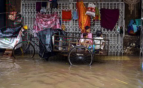 A family finds shelter on a rickshaw parked in a road side after a heavy rainfall in Kolkata on Tuesday, June 26 2018.
